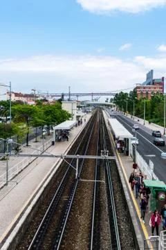Two train tracks next to a staion platform with people on it Stock Photos