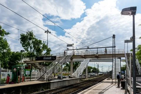 Two train tracks next to a station platform with people on it Stock Photos