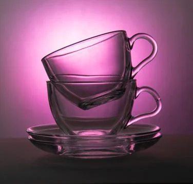 Two transparent cups and two transparent saucers on a pink background Stock Photos