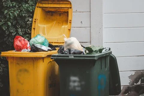 Two trash cans, one yellow and one green, are full of garbage Stock Photos
