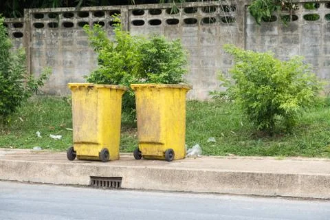 Two trash cans, yellow Some on the sidewalk on the roadside Stock Photos