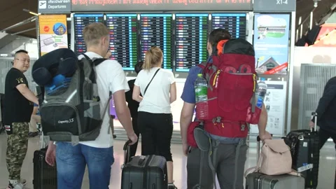 Two travel men with backpack stands back and looks schedule on scoreboard Video stock 152443372