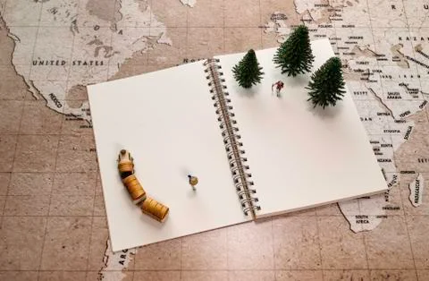 Two traveler miniatures on notebook with pine tree and wooden train Stock Photos
