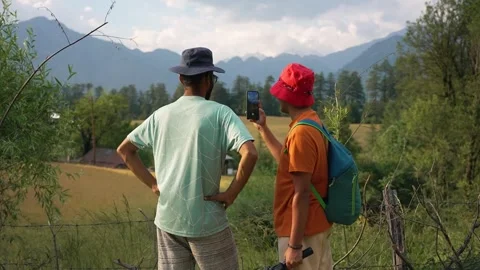 Two travelers checking a map in a mountain meadow Stock Footage 336247878