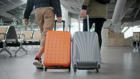 Two Travelers Pulling Suitcases Through an Airport Terminal Stock Footage 295748937
