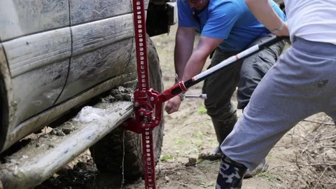 Two travelers replacing wheel of expeditionaty SUV at forest dirty road. Stock Footage