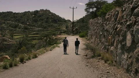Two travelers walking between mountains in Saudi Arabia View from the back. Stock Footage 113686193