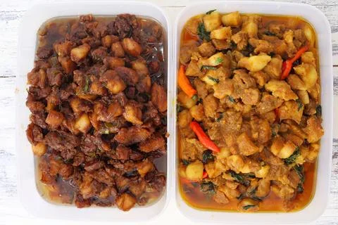 Two trays of cooked curry with vegetables and meat Stock Photos