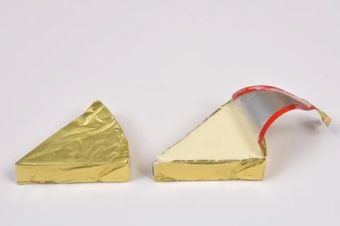 Two Triangular Cheese Portions in Gold Foil Stock Photos