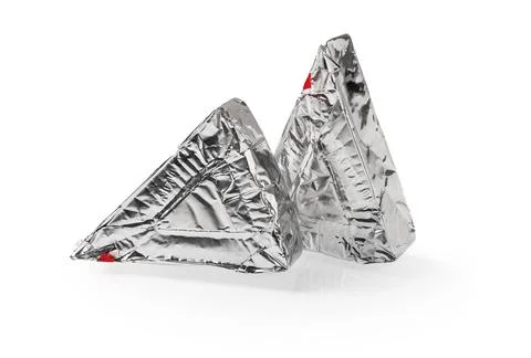 Two triangular pieces of foil wrapped processed creame cheese isolated on white. Stock Photos