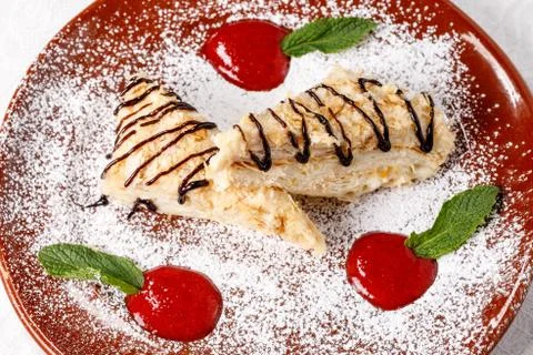 Two triangular pieces of puff dessert Napoleon. Powdered Sugar, Mint and Jam  Stock Photos