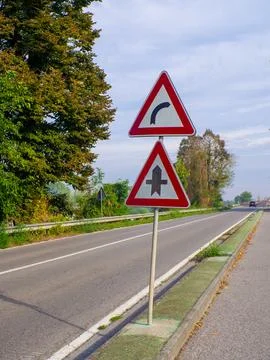 Two triangular road signs stand by a road Stock Photos