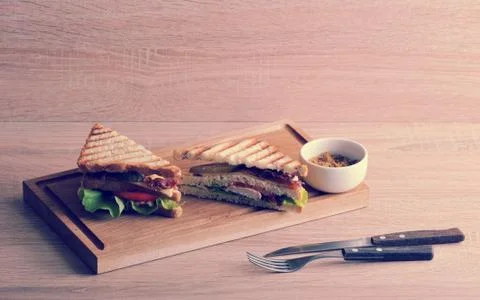 Two triangular sandwich with bacon and chicken breast on a wooden Board Stock Photos
