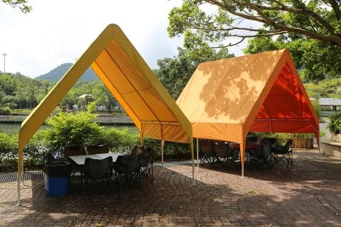 Two triangular-shaped canopy tents with gable roofs, in an orange and yello.. Stock Photos