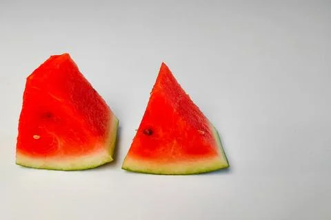 Two triangular slices of red watermelon with juicy flesh on a white backgroun Stock Photos