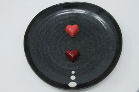 Two Truffle Candy Hearts Lined Up on an Artsy Black Plate Stock Photos