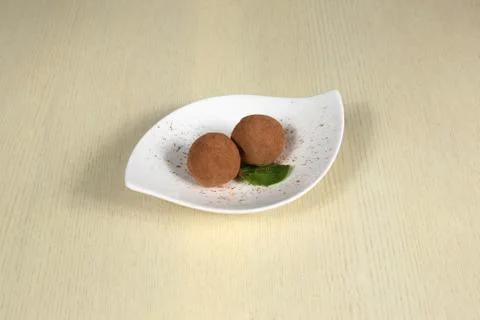 Two truffle sprinkled with cocoa on a white plate Stock Photos