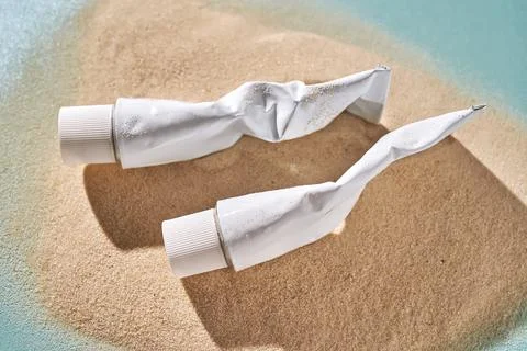 Two tubes of cream on the sand. Stock Photos