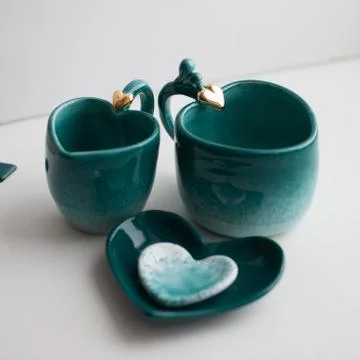 Two turquoise cups for tea or coffee on the white table Stock Photos