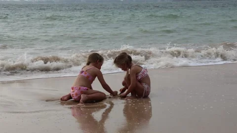 Two twin sisters playing on the beach in a surf wave Video stock 323743456