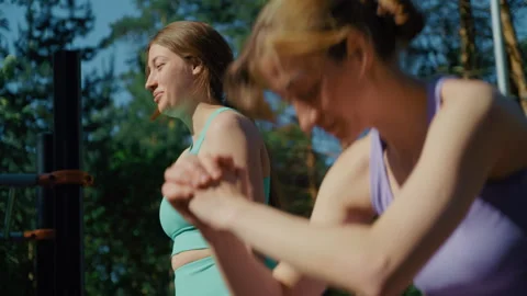 Two twin sisters training together at an outdoor gym Видео 336960874