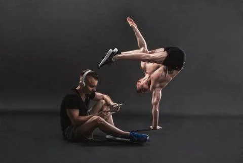 Two twins on a black background, one sits and listens to music, the other st Stock Photos