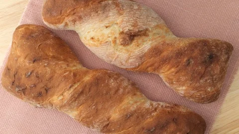 Two twisted baguettes rotating on a pink tablecloth Stock Footage 344604045