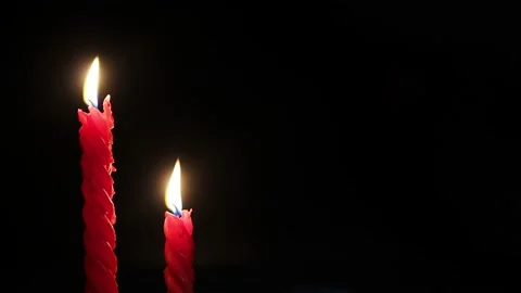 Two twisted red candles burn on a black background. Close-up. Video stock 161891854