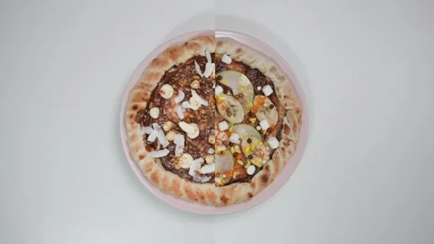 Two types of chocolate pizza spinning on a pink plate. White background. Video stock 260044473