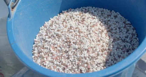 Two types of fertilizer are mixed together in a container before application. Stock Footage 323344014