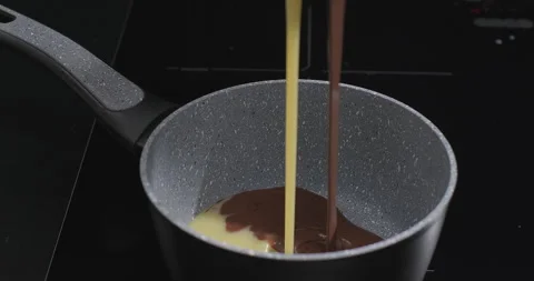 Two types of melted chocolate flowing into a pan, dark and white chocolate Stock Footage 258391552