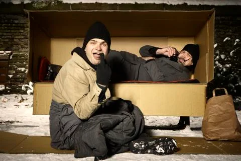 Two ugly men sharing paper box in winter city park Stock Photos