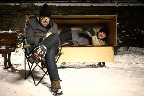 Two ugly men sharing paper box in winter city park Stock Photos
