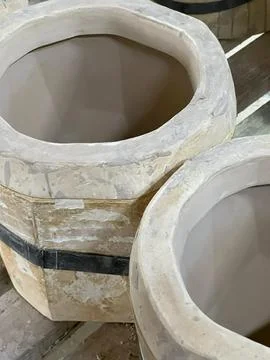 Two unglazed ceramic pots sit on a wooden shelf in a workshop, highlighting.. Stock Photos