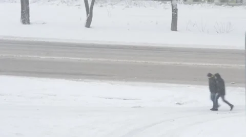 Two unidentifiable men walking along the road in snow Stock Footage 46990364