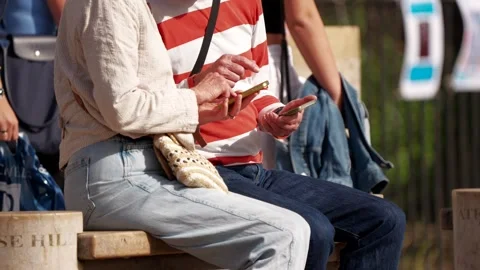 Two unidentifiable people using phones on a public street as people walk past 動画素材 283547133
