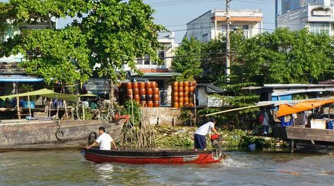 Two unidentified men working on a small wooden boat on Mekong River Stock Photos