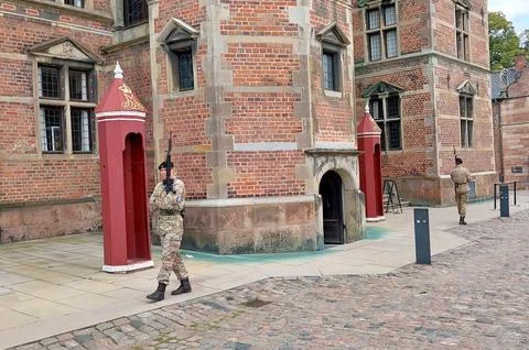 Two uniformed guards stand on duty and patrol in front of the historic brick Stock Photos
