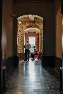 Two uniformed men talking inside an ornate historic palace corridor with Stock Photos