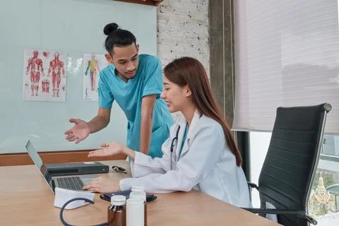 Two uniformed young doctors work in medical clinic office. Stock Photos