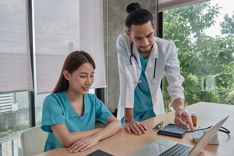 Two uniformed young doctors work in medical clinic office. Stock Photos