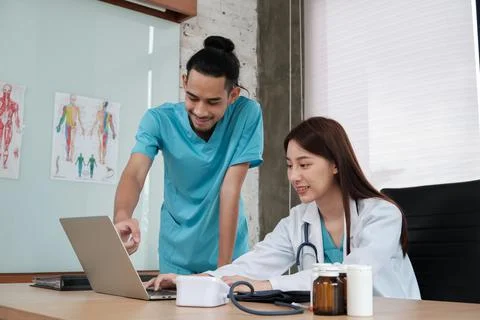 Two uniformed young doctors work in medical clinic office. Stock Photos