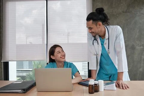 Two uniformed young doctors work in medical clinic office. Stock Photos