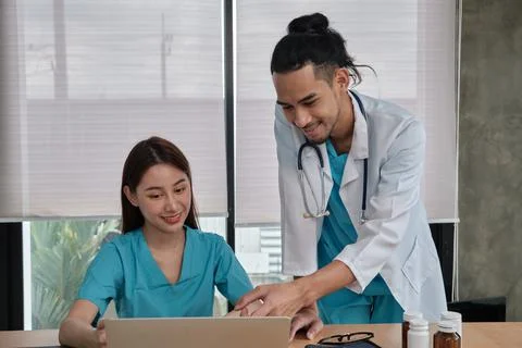 Two uniformed young doctors work in medical clinic office. Stock Photos