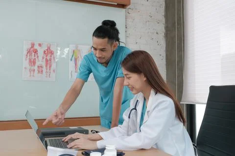 Two uniformed young doctors work in medical clinic office. Stock Photos
