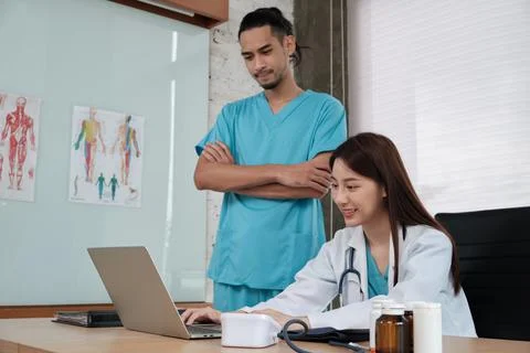 Two uniformed young doctors work in medical clinic office. Stock Photos