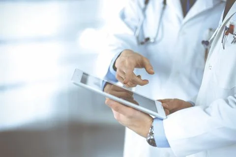 Two unknown doctors with stethoscopes discussing medical exam resoults, standing Stockfoto's