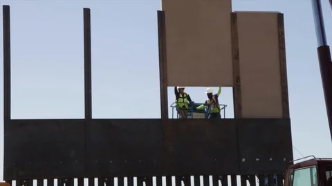 Two unknown men on a telehandler cleaning before placing a concrete panel Stock Footage 99043324