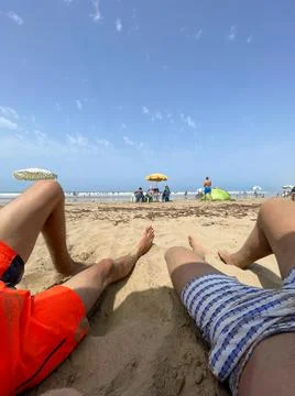 Two unrecognizable guys' legs with a view of the beach in Asilah Stock Photos