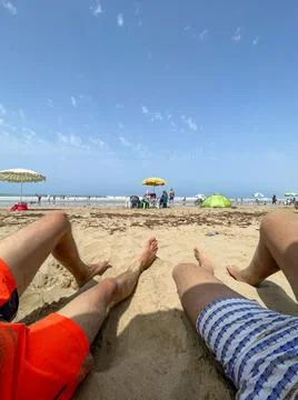 Two unrecognizable guys' legs with a view of the beach in Asilah Stock Photos